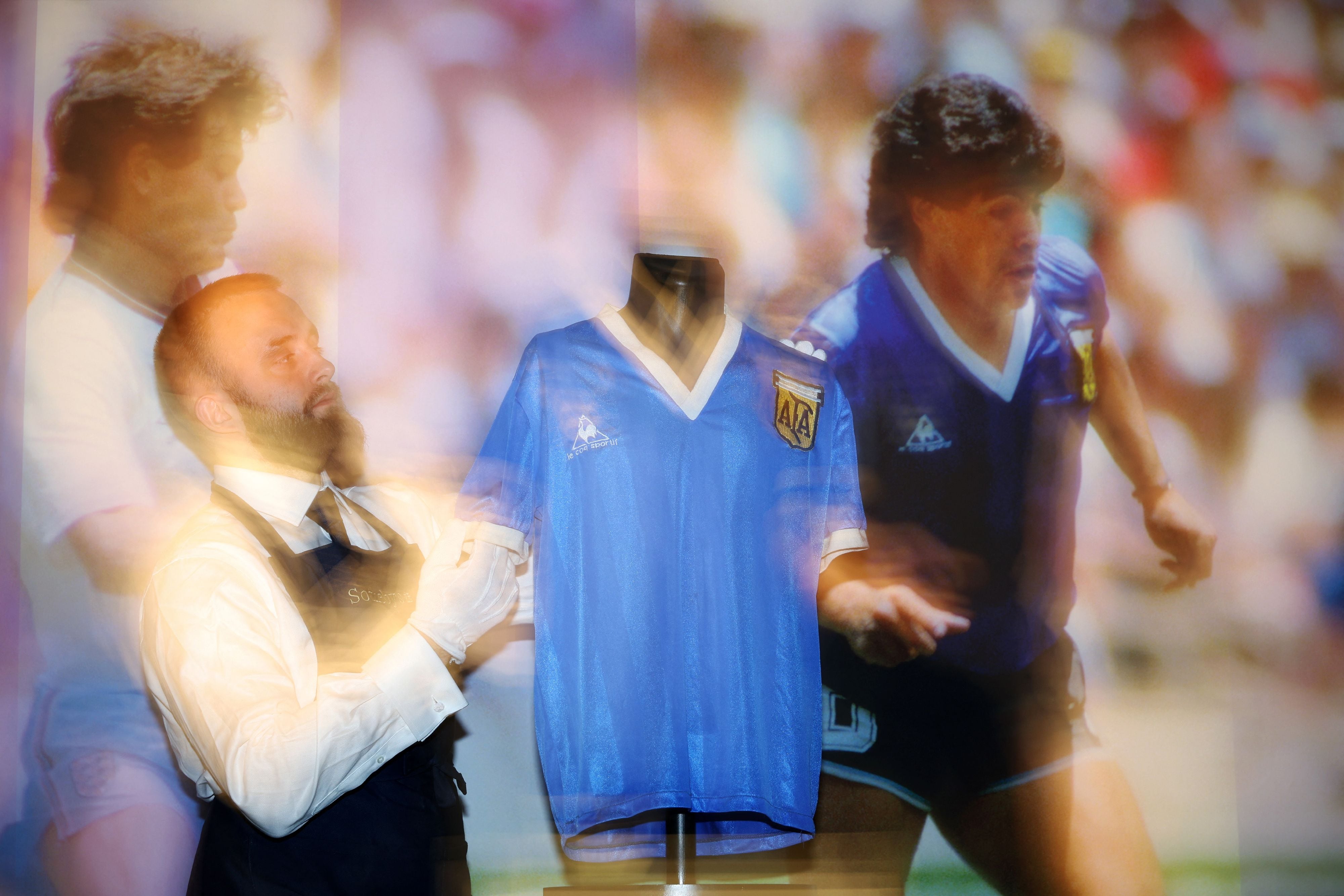 Uno de los técnicos de Sotheby&#039;s, junto a la camiseta de Maradona subastada por 8,4 millones de euros (Photo by ADRIAN DENNIS / AFP) (Photo by ADRIAN DENNIS/AFP via Getty Images).