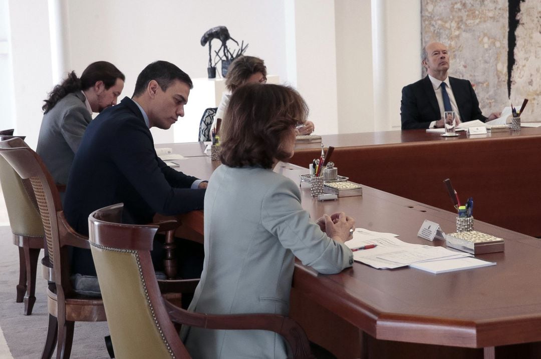 Fotografía facilitada por la Moncloa que muestra al presidente del Gobierno, Pedro Sánchez (c), que preside la reunión de Consejo de Ministros, junto al vicepresidente Pablo Iglesias (i) y la vicepresidenta, Carmen Calvo (d), en el Palacio de la Moncloa a en Madrid, este sábado, para aprobar el decreto que declara el estado de alarma. 