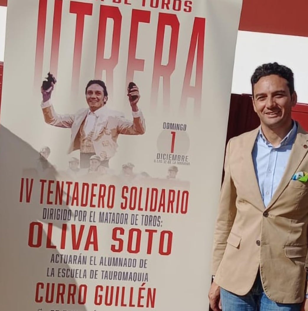 Oliva Soto posa junto al cartel del tentadero solidario del 1 de diciembre en Utrera