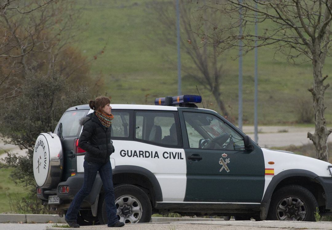 Un coche de la Guardia Civil mientras una vecina pasea por la zona. 