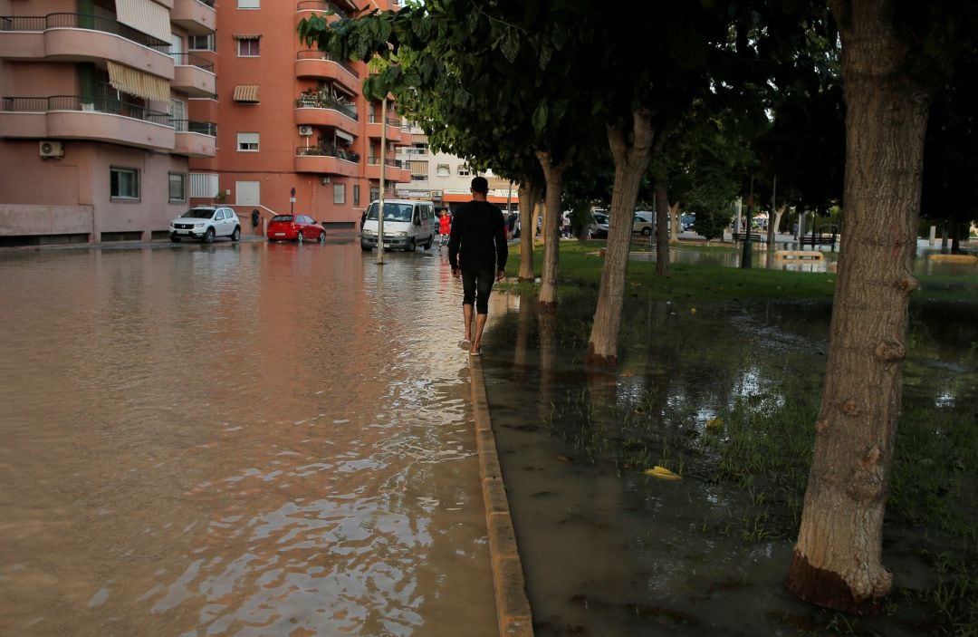 Un hombre pasea por una calle inundada en Orihuela