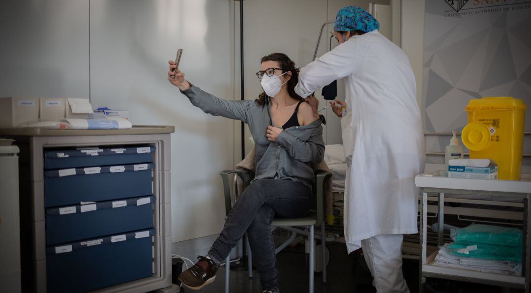 Una enfermera vacuna a un profesional sanitario con la vacuna de Pfizer-BioNtech contra el COVID-19.