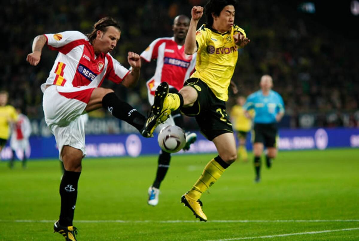 El jugador del Sevilla Alexis y el de l Borussia Dortmund Shinji Kagawa luchan por un balón dividido