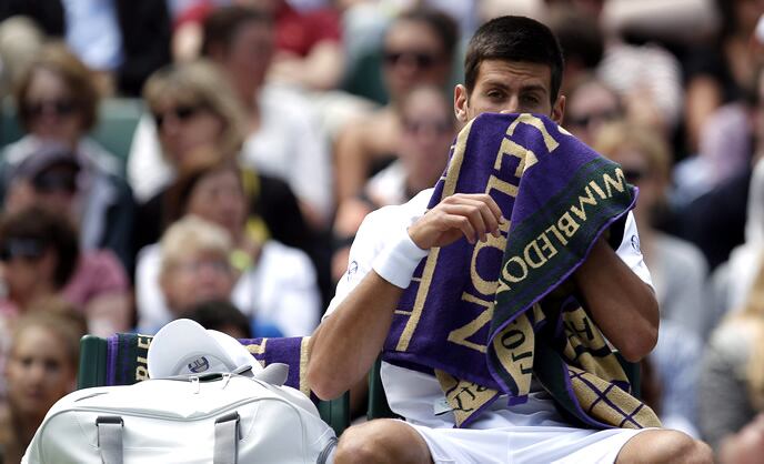 El tenista serbio Novak Djokovic se seca con una toalla durante su partido de la segunda ronda del torneo de Wimbledon disputado contra el sudafricano Kevin Anderson