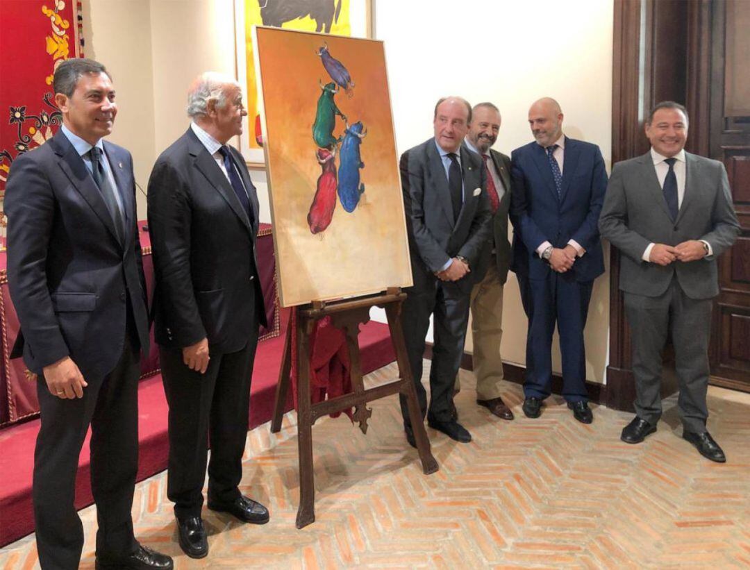 De izquierda a derecha, junto al cartel pictórico del festival del 12 de octubre el día de su presentación, Marcelino Serrano, hermano mayor del Baratillo; Ramón Valencia, gerente de la Empresa Pagés; Joaquín Moeckel, coordinador del festival; el pintor Luis Rizo; Sergio Sopeña, hermano mayor de la Esperanza de Triana; y Ricardo Sánchez, delegado del Gobierno de la Junta en Sevilla