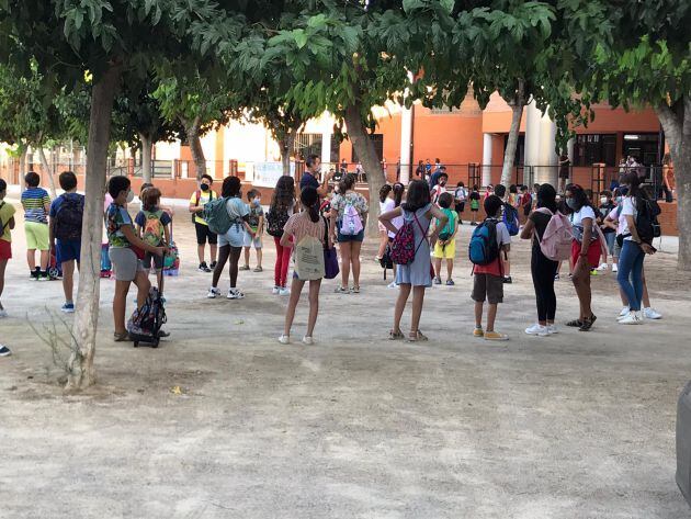 Los niños guardan fila en el patio guardando la distancia de seguridad antes de acceder al aula