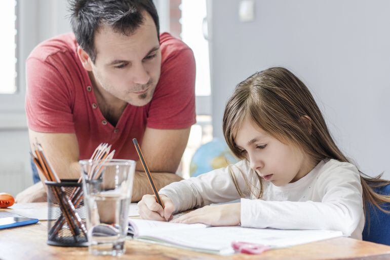 Un padre ayuda a su hija a hacer los deberes. 