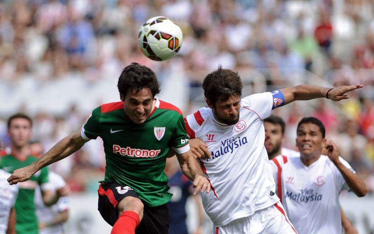 Coke defiente un balón ante Xabier Etxeita, durante el Sevilla-Athletic