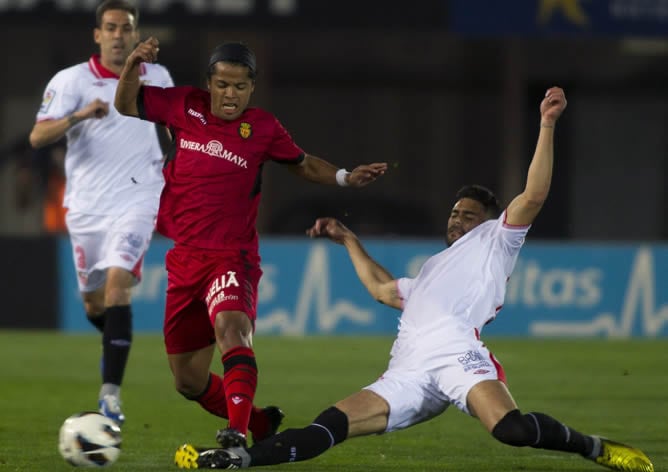 El delantero mexicano del RCD Mallorca Giovani Dos Santos y el defensa del Sevilla FC, Alberto Botía, luchan por el balón durante el partido correspondiente a la vigésima séptima jornada de Liga disputado en el Iberostar Estadio de Palma