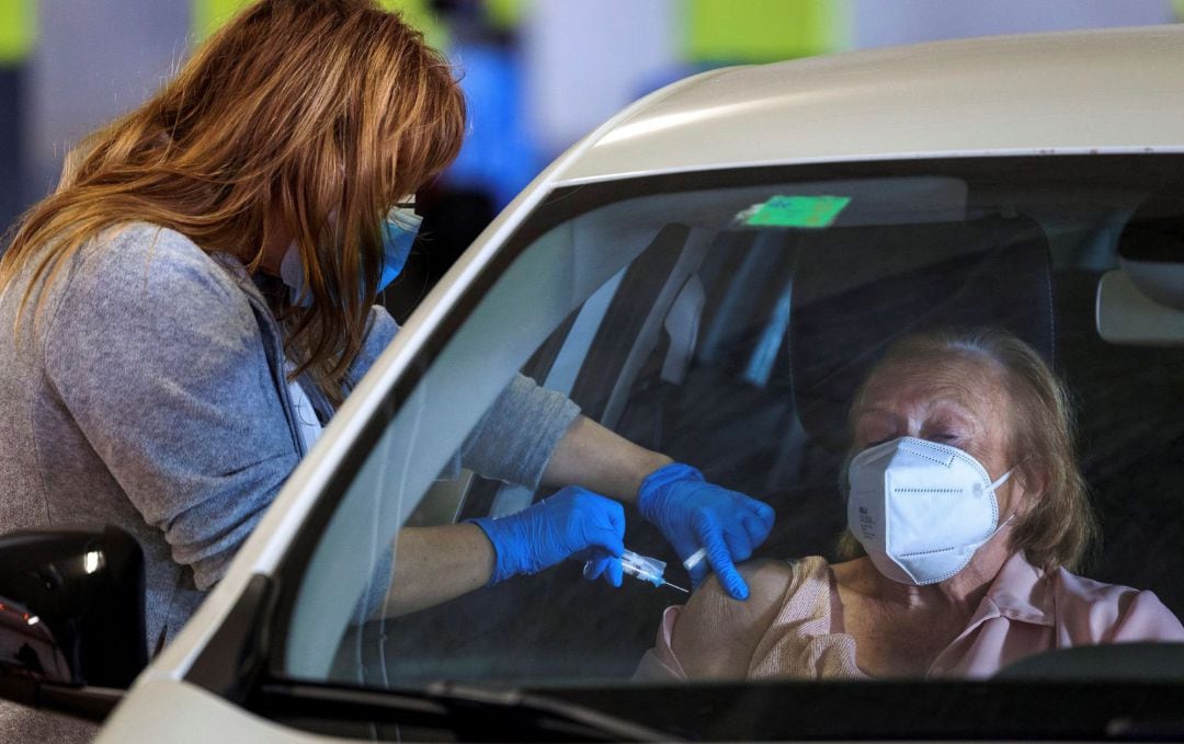 Una sanitaria inyecta una vacuna a una mujer.