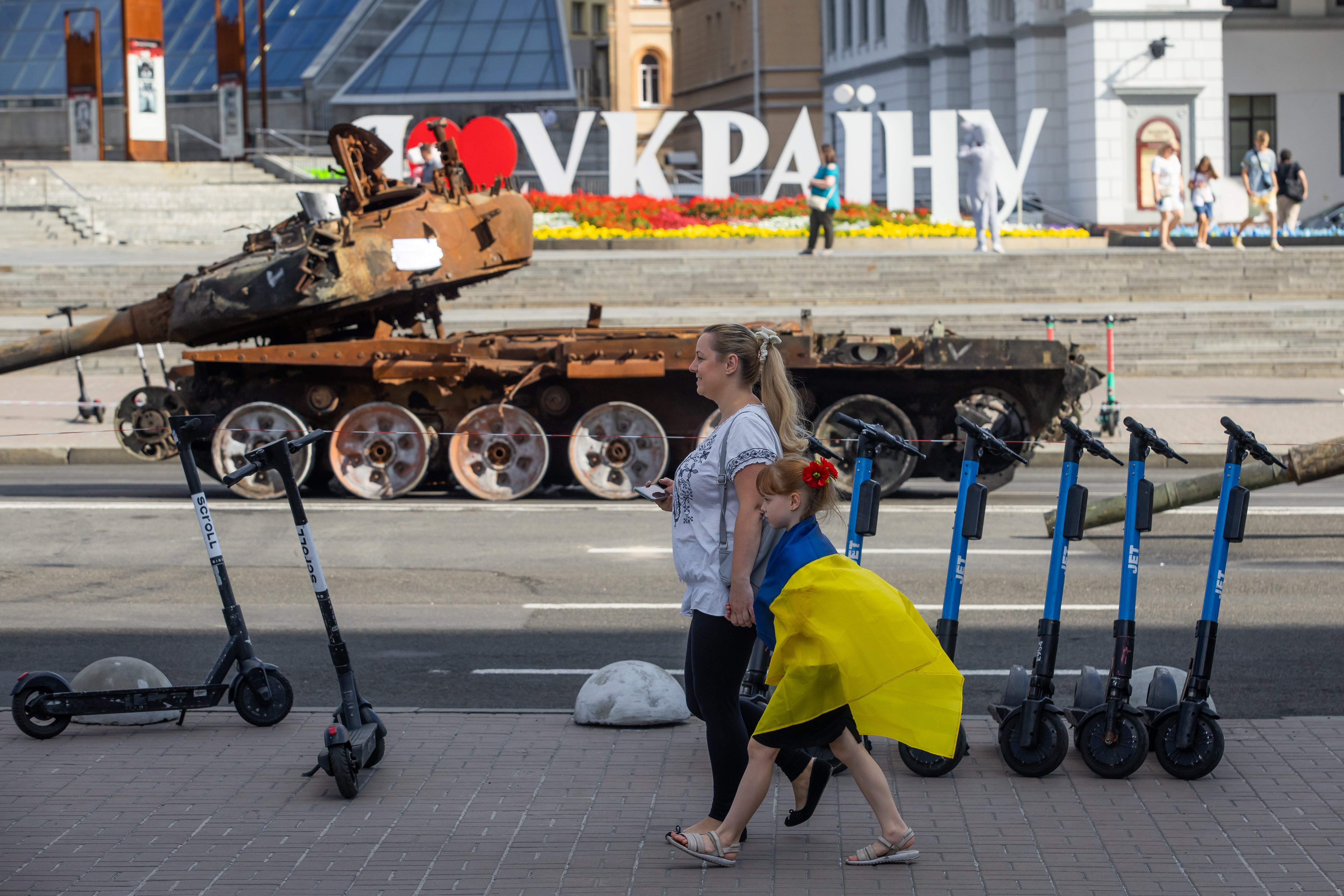 Una mujer y su hija pasan delante de un tanque ruso destruido exhibido en las calles de Kiev con motivo del Día de la Independencia de Ucrania