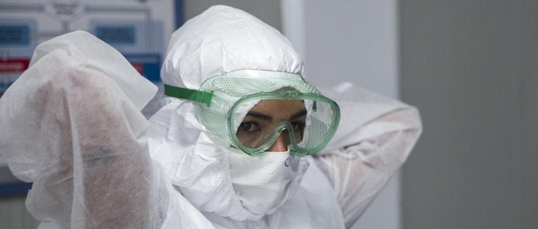 Una profesional sanitaria se coloca un equipo de protección
