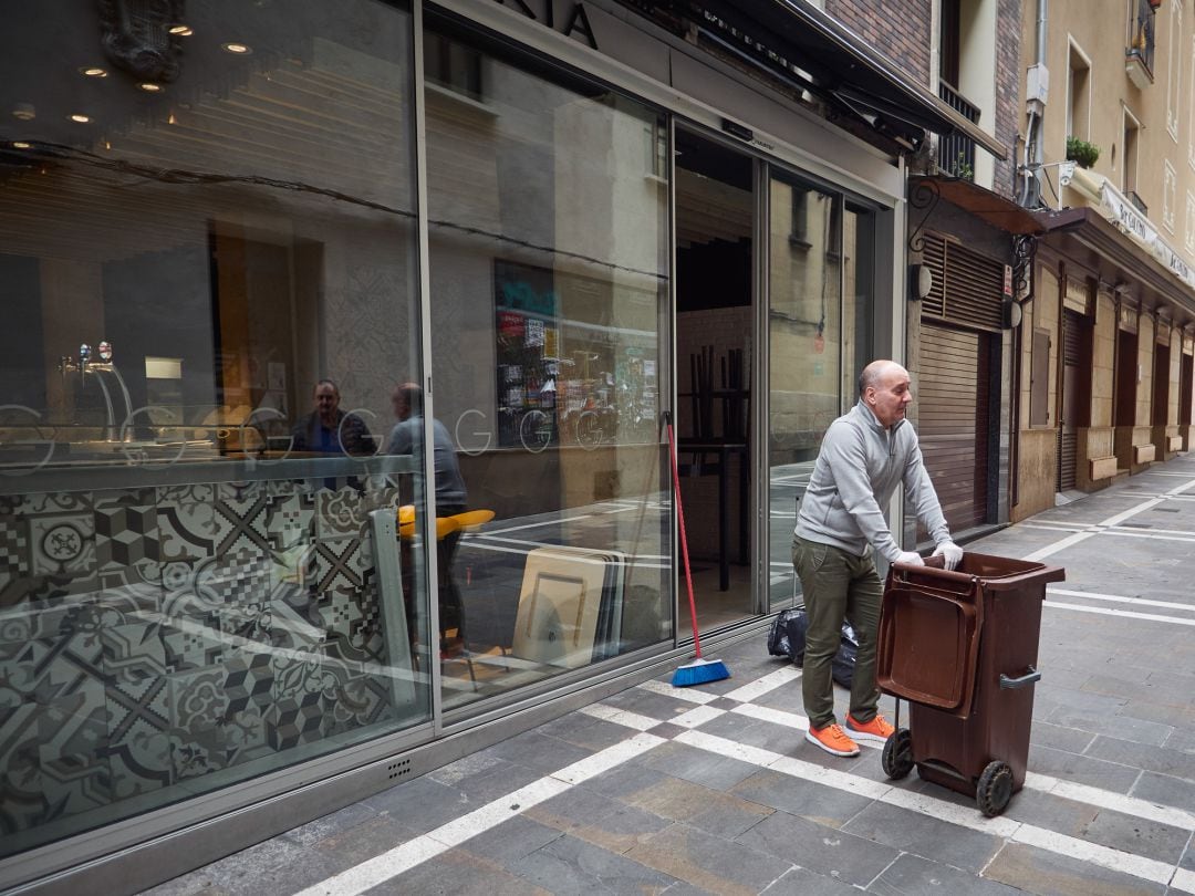 El dueño de un bar limpia su establecimiento cerrado en una calle de Pamplona 