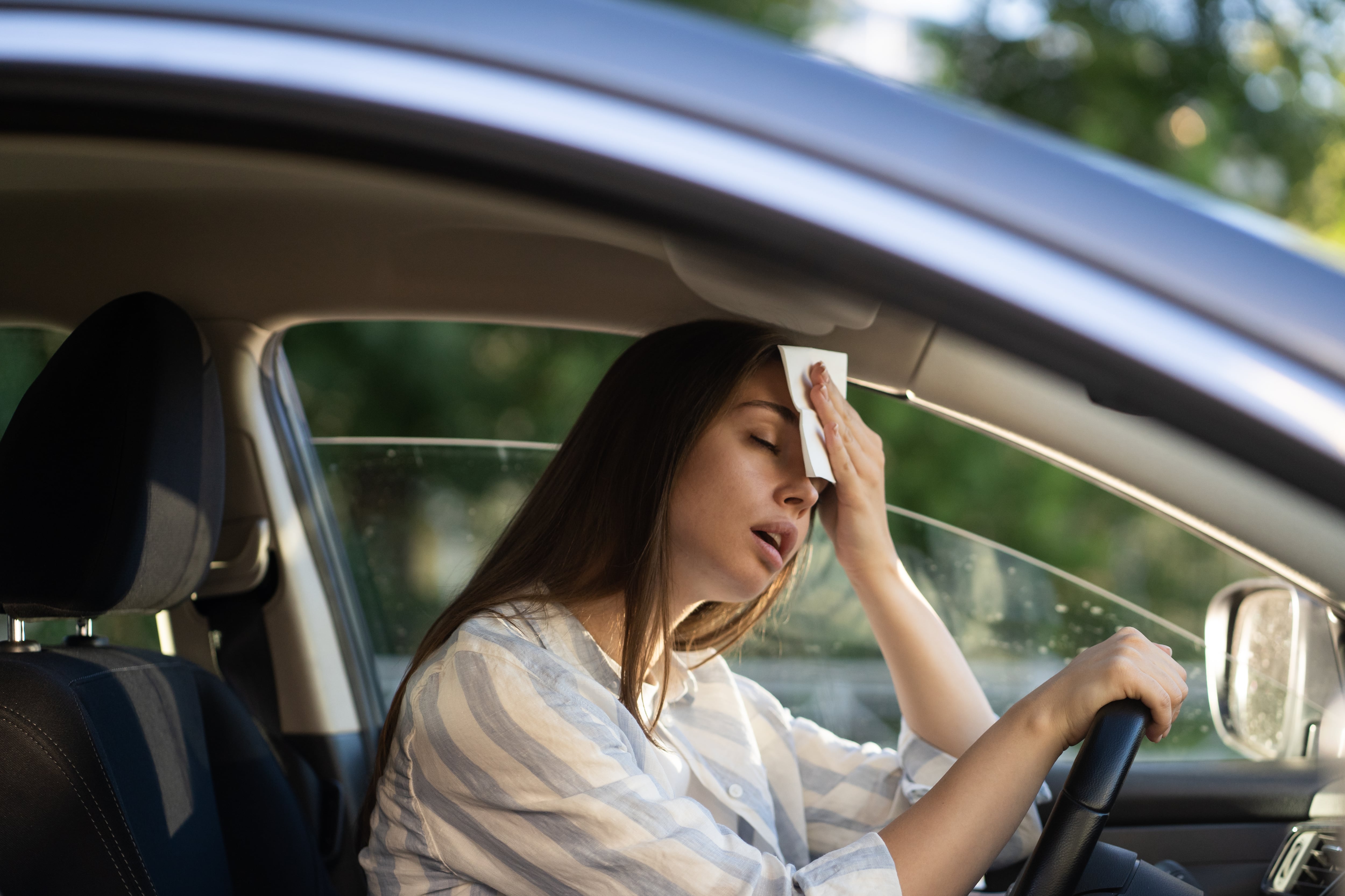 Una mujer se limpia el sudor en el coche.