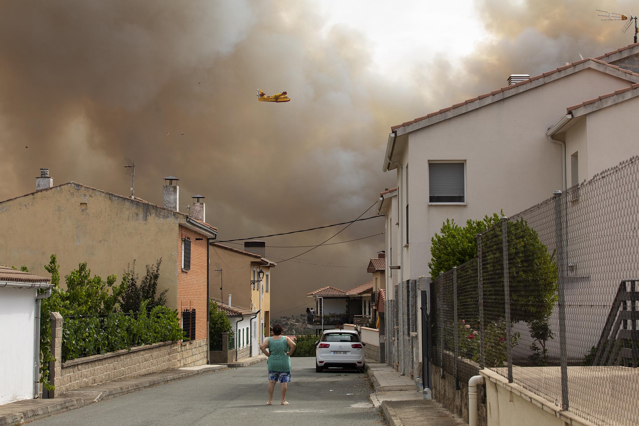 Una mujer observa, en El Barraco, cómo trabaja el hidroavión del Ejército durante las labores de extinción del incendio del pasado sábado