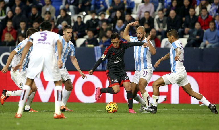 El delantero chileno del Celta de Vigo Fabián Orellana (c) controla el balón rodeado de jugadores del Málaga CF, durante el partido de la décimo octava jornada de Liga en Primera División que se disputó en el estadio de La Rosaleda, en Málaga
