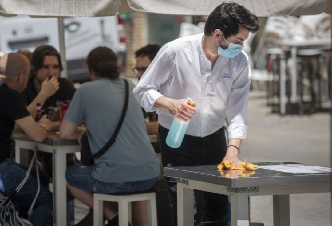 Un camarero desinfecta lamesa de la terraza del establecimiento