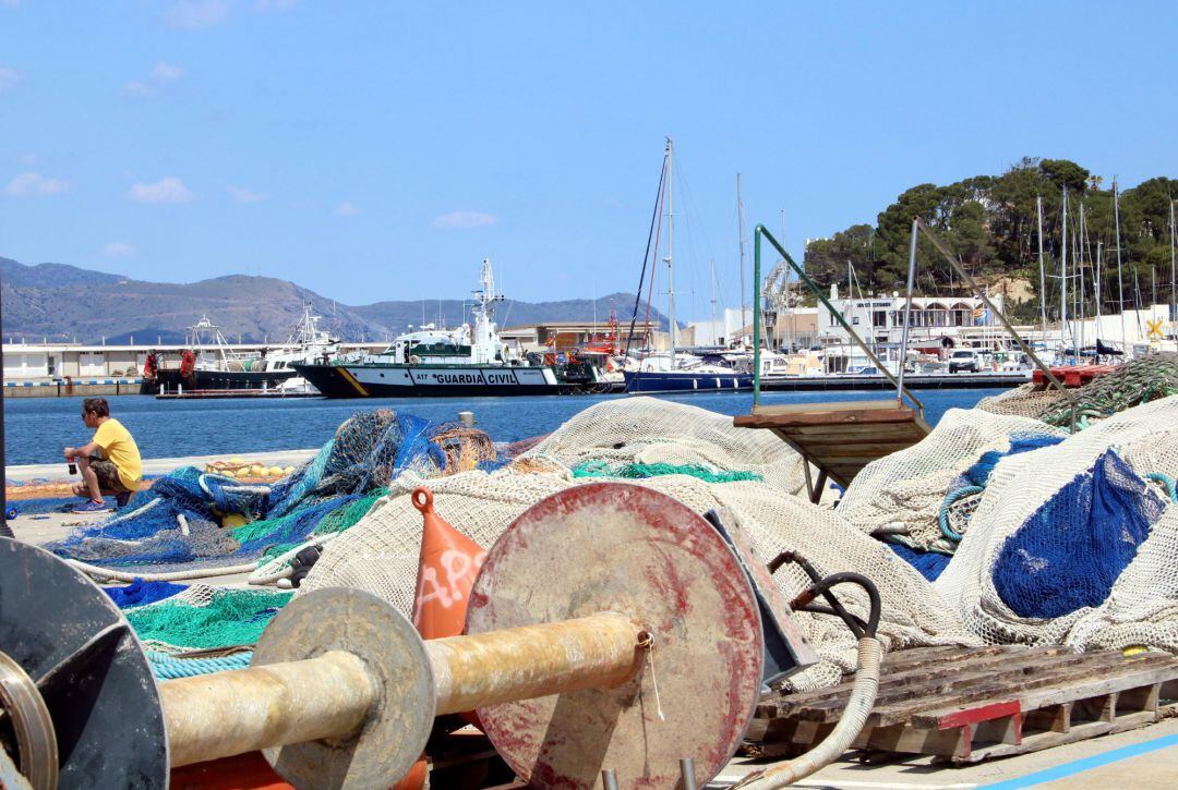 El moll del Port de la Selva amb xarxes i un pescador feinejant 