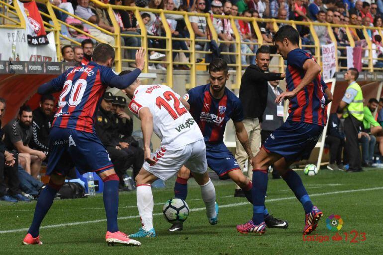 Tres jugadores del Huesca rodean a Rodri en un lance del partido de la primera vuelta