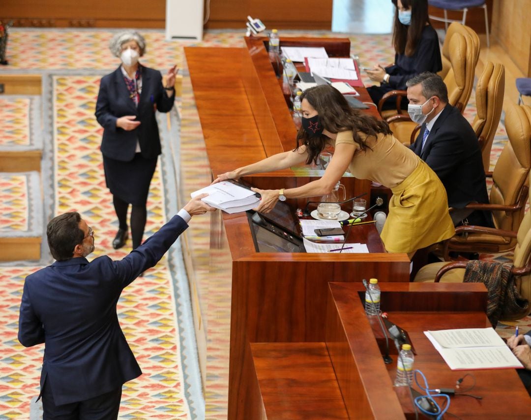 El consejero de Hacienda, Economía y Empleo de la Comunidad de Madrid, Javier Fernández-Lasquetty (i), entrega a la presidenta de la Mesa de la Comunidad de Madrid, Eugenia Carballedo (d), copias de contrataciones de emergencia en la región por la crisis del Covid-19, en una sesión plenaria de la Cámara madrileña, a 11 de noviembre de 2021, en Madrid (España). 