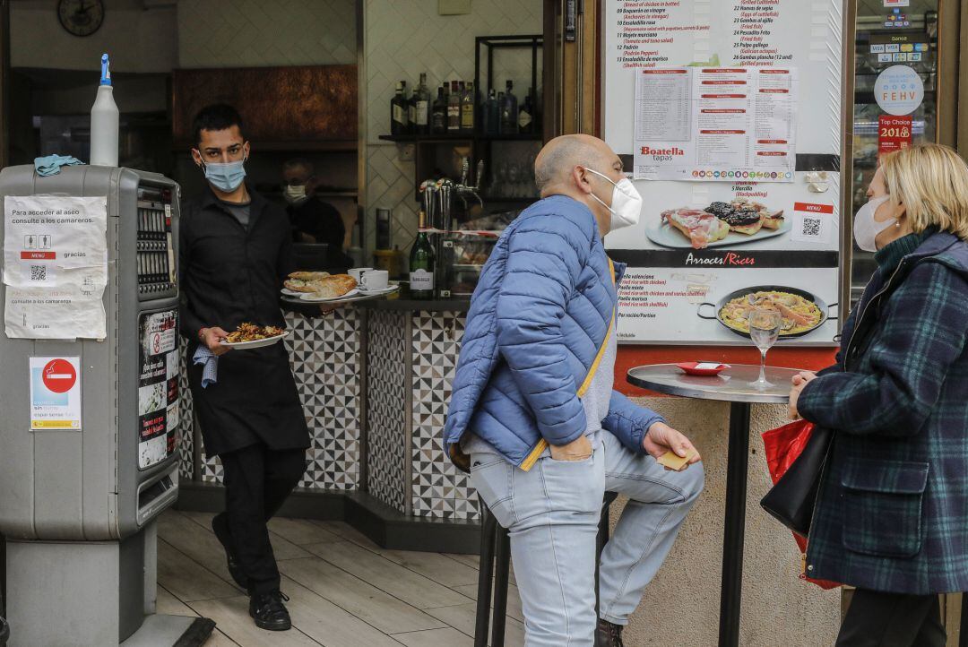 Un camarero atiende a varios clientes en una terraza en València