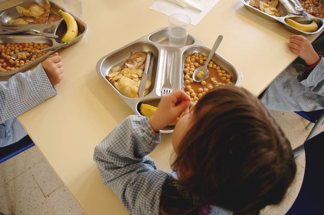 Una niña come en un comedor escolar.