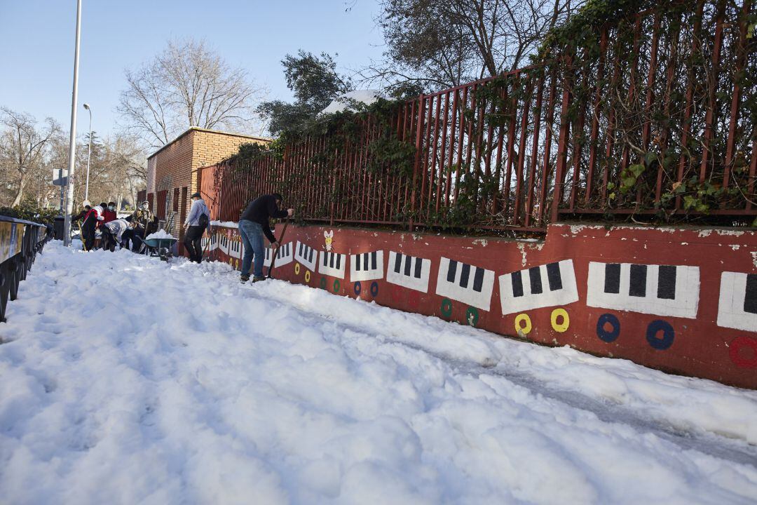 Varios familiares colaboran en la limpieza del hielo y la nieve en las inmediaciones del colegio Amadeo Vives tras la gran nevada por el paso de la borrasca &#039;Filomena&#039;, en Madrid.