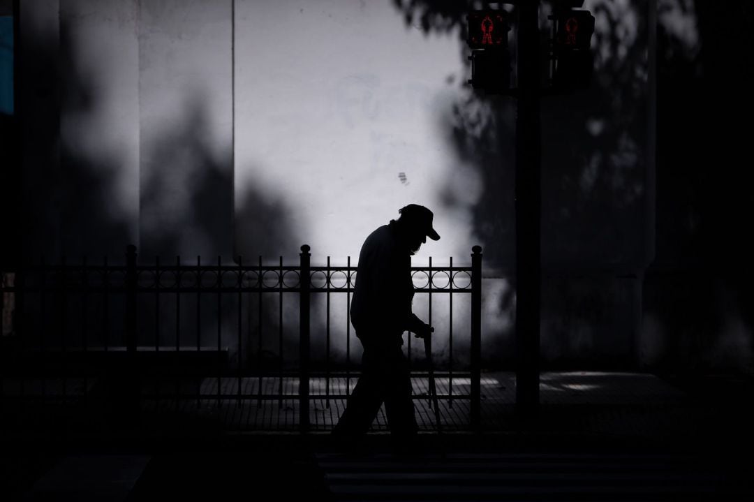 Silueta de un anciano que camina por una calle de Buenos Aires hoy lunes, luego de que el Gobierno anunciara el uso obligatorio de tapa boca a partir del 15 de abril. Argentina abrió un nuevo tramo de la cuarentena social obligatoria para frenar los contagios por el coronavirus, que durará hasta al menos el 26 de abril y en el que, además de aceptar excepciones como la reapertura de los bancos, se promoverá el uso de la mascarilla en lugares públicos cerrados.