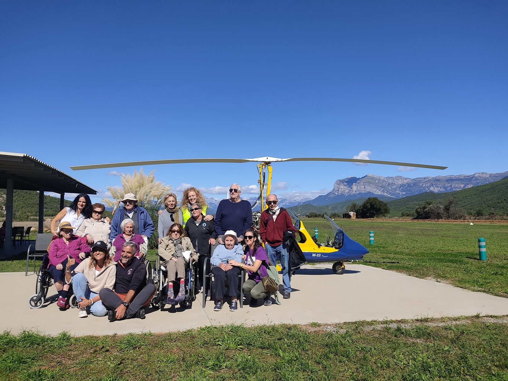 Foto de familia con personas usuarias y trabajadoras de la residencia de mayores en el aeródromo de Coscojuela