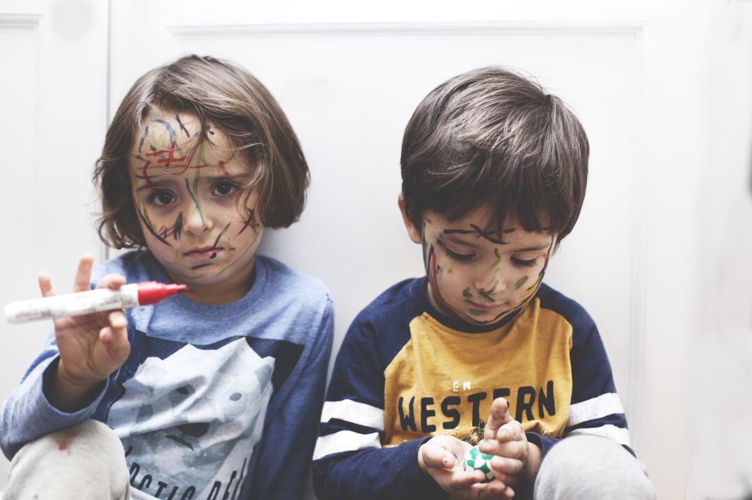 Dos niños jugando con pinturas. 