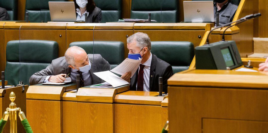 El lehendakari Iñigo Urkullu (d) conversa con el vicelehendakari primero y consejero de Seguridad, Josu Erkoreka, durante el pleno del Parlamento Vasco 