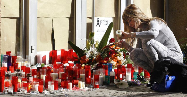 A woman lights a candle in memory of the teacher who yesterday resulted killed at the Joan Fuster Institute in Barcelona, on April 21, 2015. A 13-year-old boy armed with a crossbow and knife killed a teacher and wounded four others at his school in Barcelona on April 20, 2015 before being subdued, police and witnesses said. Among the injured were a Spanish language teacher and her daughter, also a student at the school, according to Spanish media reports. AFP PHOTO / QUIQUE GARCIA