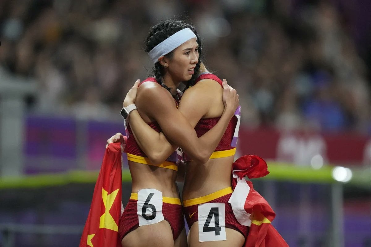 Las atletas Lin Yuwei y Wu Yanni se abrazan después de la carrera formando de forma fortuita el número 64