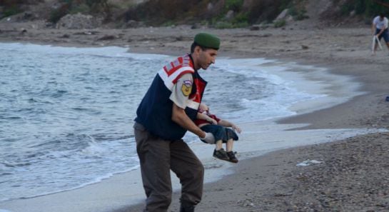 Un agente de la gendarmería turca recoge el cadáver del menor fallecido cauando intentaba llegar a Europa con su familia. /