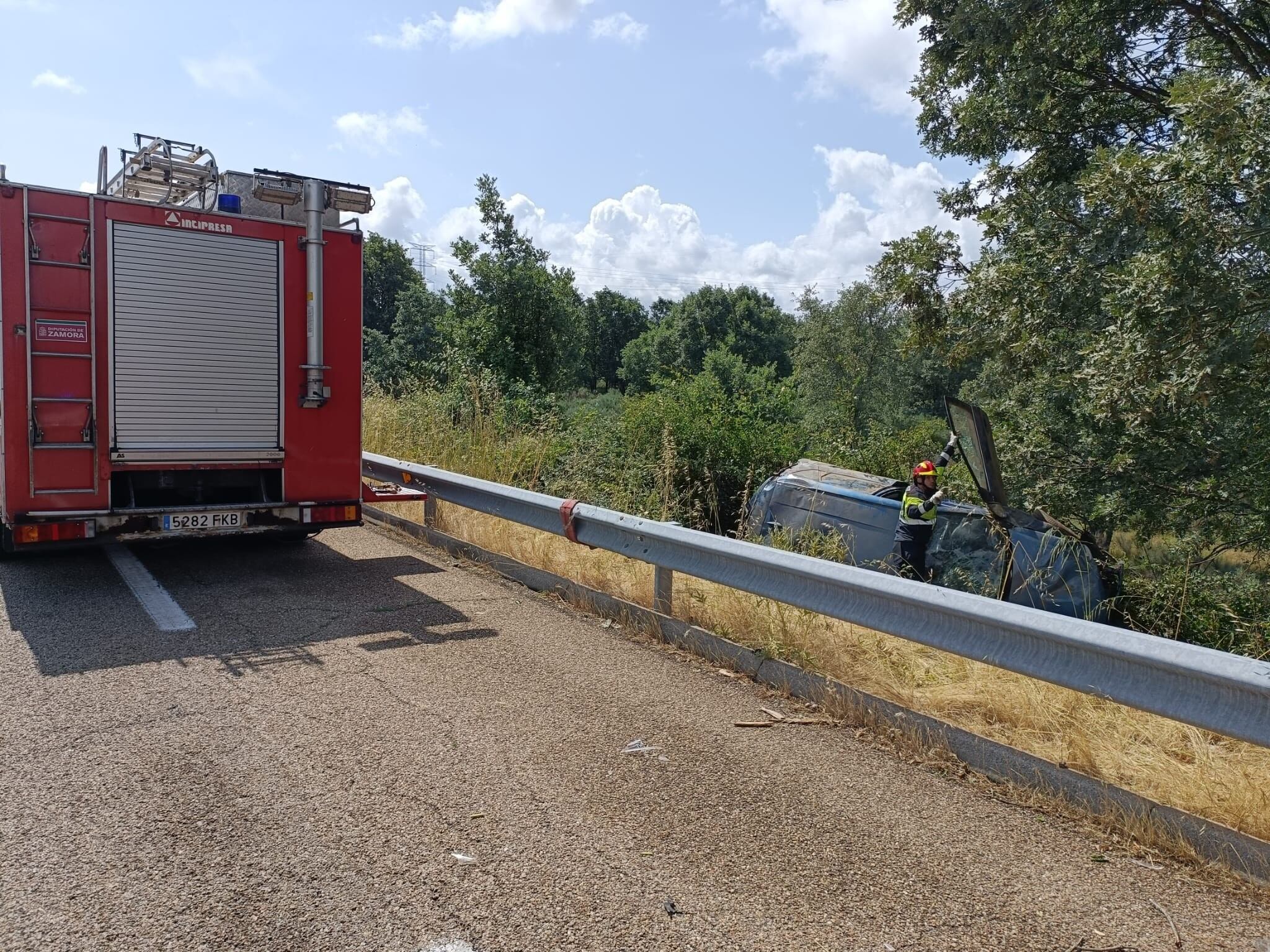 Uno de los bomberos junto al coche siniestrado