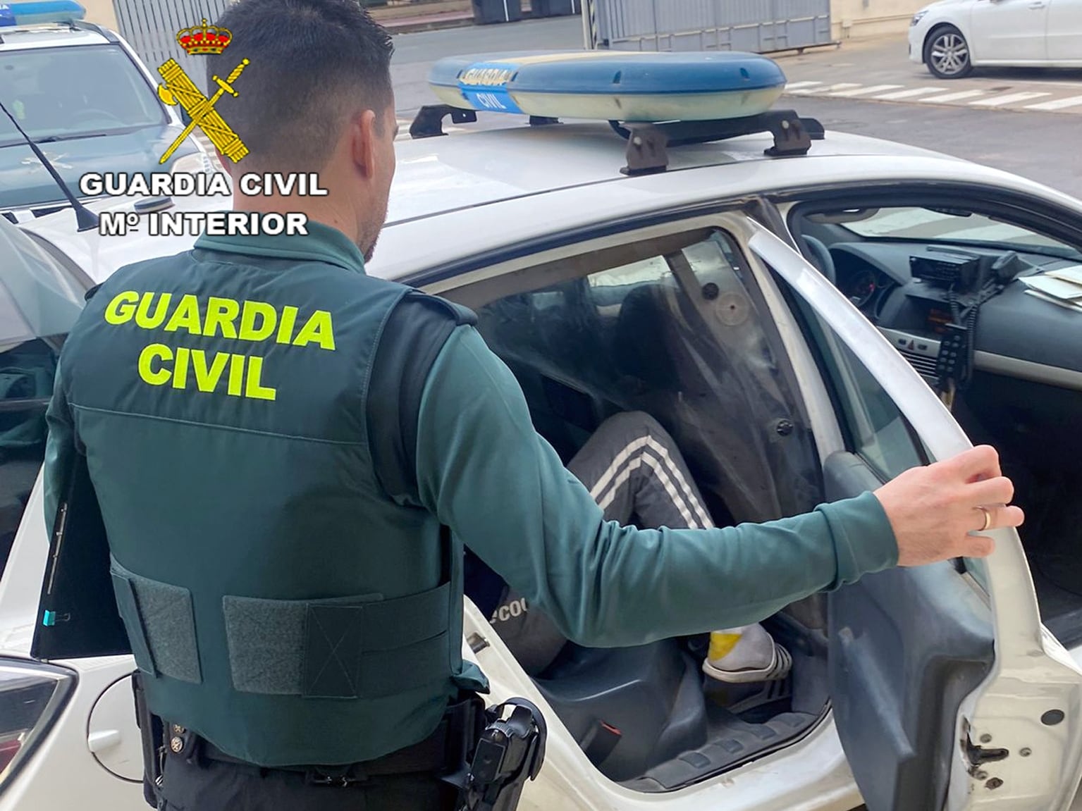 Un agente de la Guardia Civil introduce en un vehículo a uno de los dos detenidos