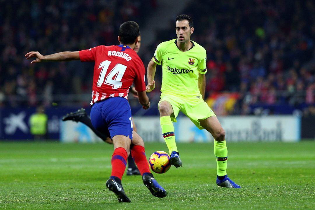 El centrocampista del FC Barcelona Sergio Busquets (d) juega un balón ante Rodrigo, del Atlético de Madrid, durante el partido de Liga en Primera División que disputan esta noche en el estadio Metropolitano. 