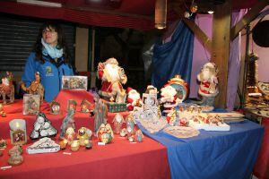 Una mujer atiende un puesto de belenes y figuras navideñas en el mercado navideño ubicado en los Paseos de San Francisco de Cuéllar