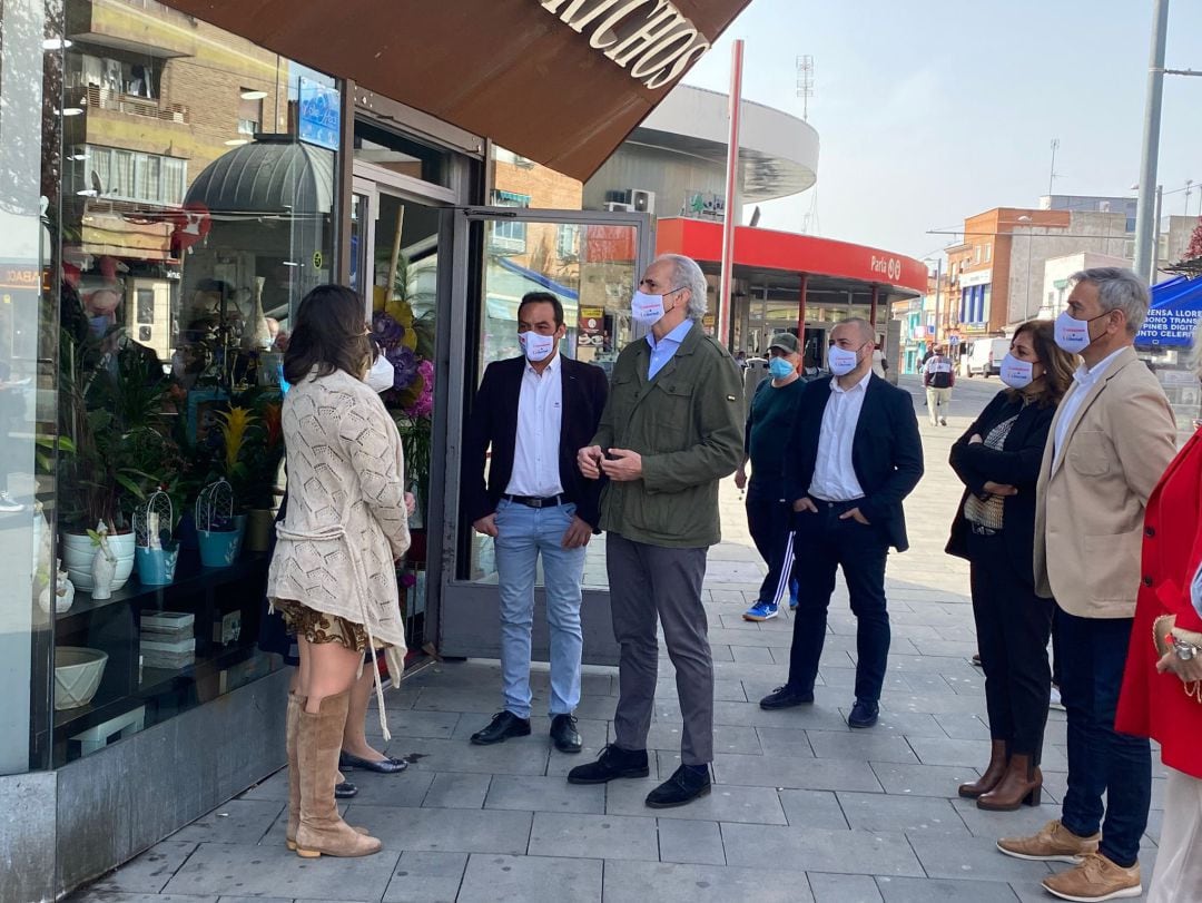 Enrique Ruiz Escudero (c) y el portavoz del PP en Parla, José Manuel Zarzoso (3i) conversan con algunos comerciantes en las inmediaciones de la estación de Cercanías.