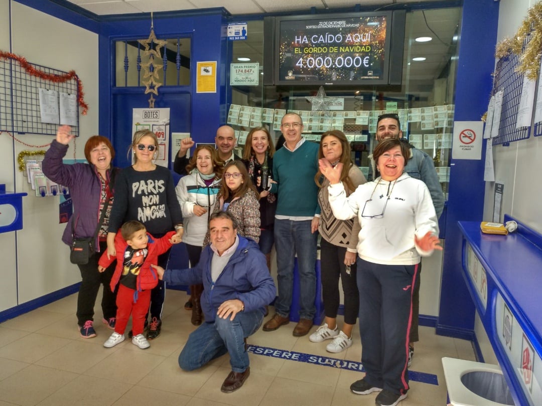 Los hermanos Mari Carmen y Leo Torres en el centro, brindan con vecinos de la administración que regentan en Villacarrillo tras dar el Gordo de Navidad