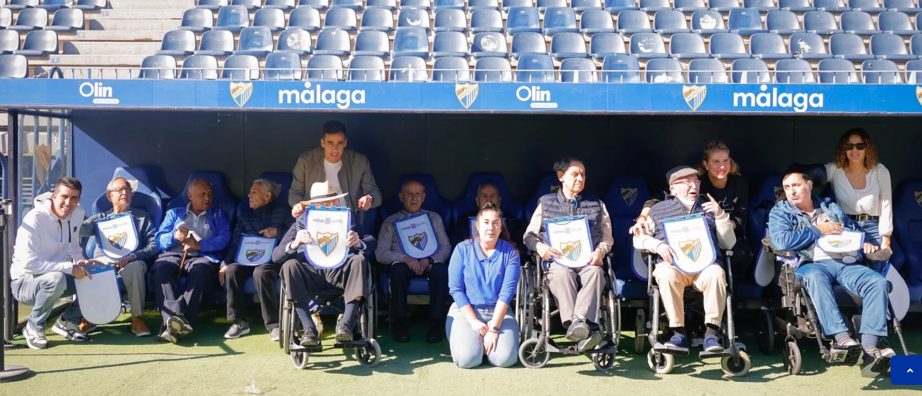 Los mayores que participaron en el taller posan en el banquillo de La Rosaleda