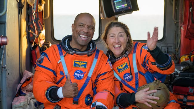 Fotografía cedida con la NASA donde aparece el piloto de la misión Artemis II, el astronauta Victor Glover (i), y la especialista de misión, la astronauta Christina Koch (d), saludando desde un helicóptero MH-60 Seahawk de la Armada estadounidense tras salir de la nave espacial Orion este viernes, en el océano Pacífico, frente a la costa de California (Estados Unidos).