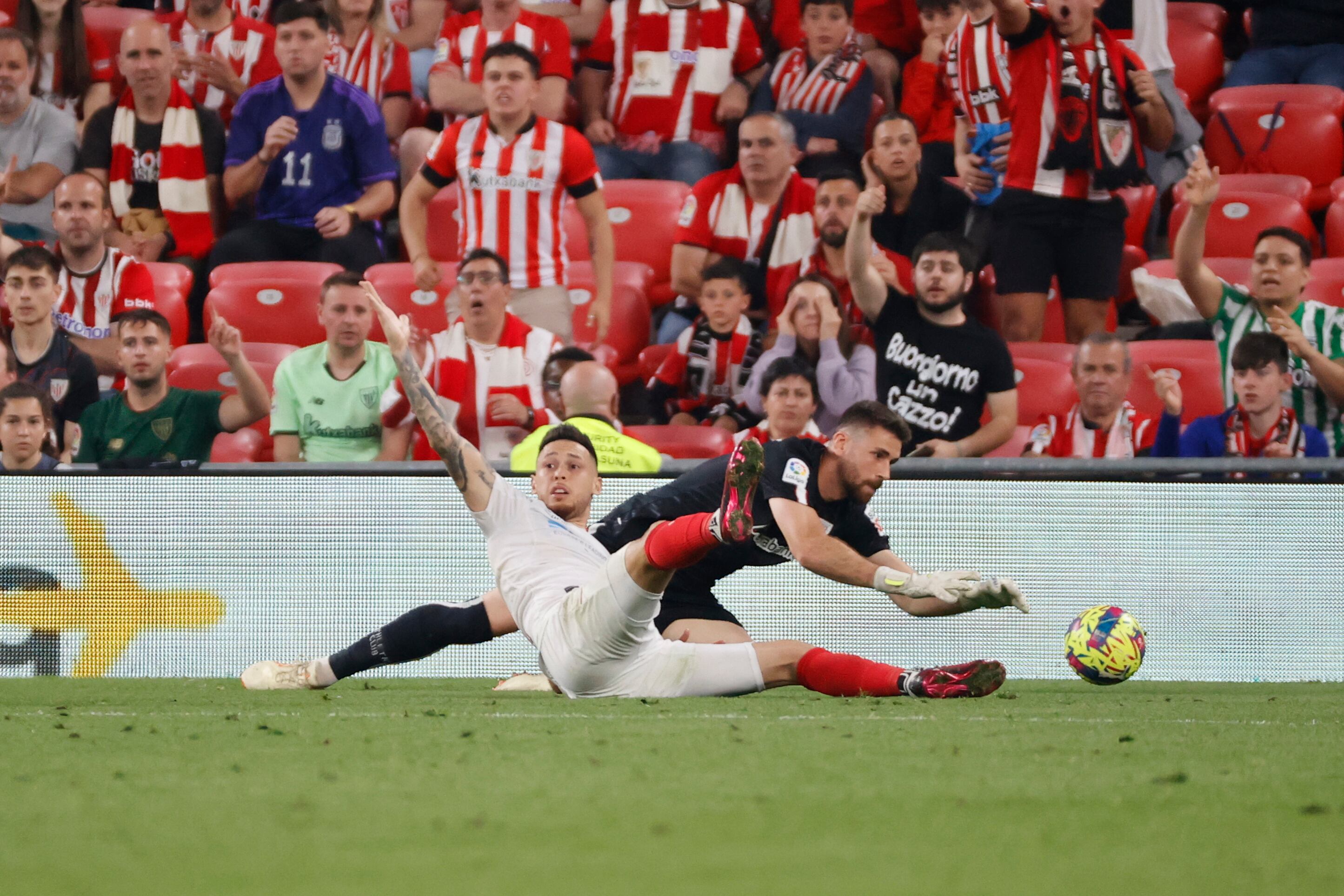 BILBAO, 27/04/2023.- El centrocampista del Sevilla Lucas Ocampos (i) cae ante el portero Unai Simón, del Athletic, durante el partido de LaLiga Santander entre el Athletic de Bilbao y el Sevilla que disputan este jueves en el estadio de San Mamés, en Bilbao. EFE/Luis Tejido
