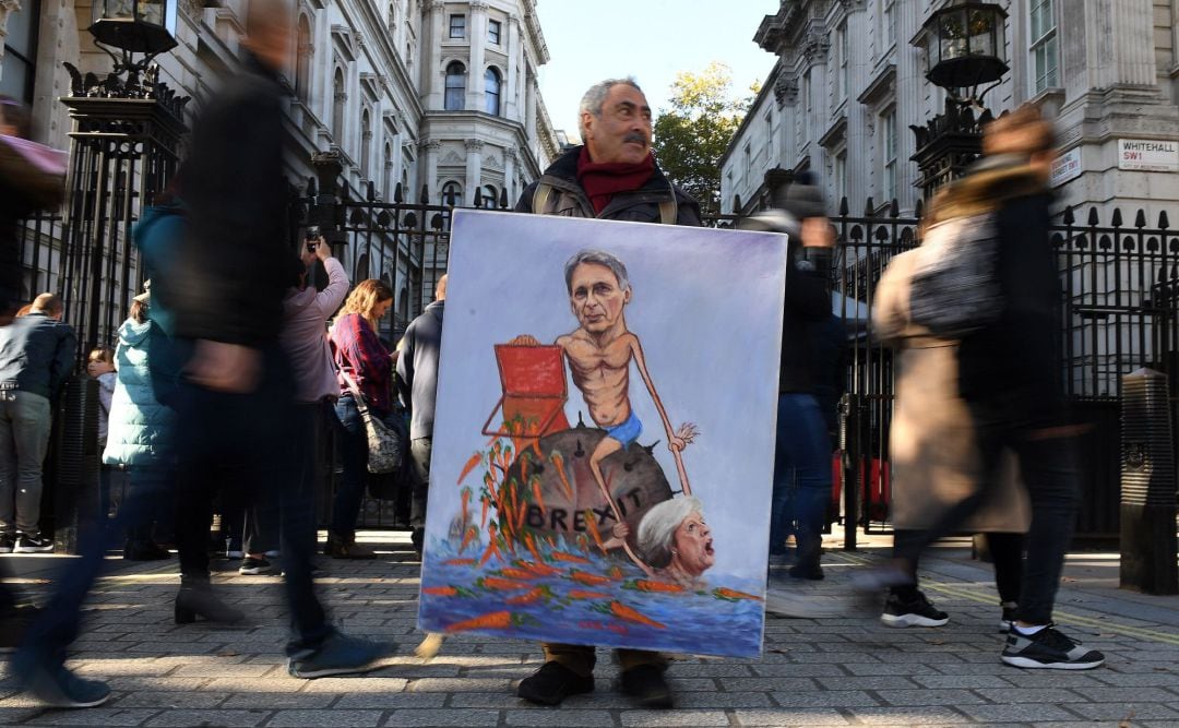 El artista satírico Kaya Mar exhibe una obra en la que retrata al ministro de economía británico, Philip Hammond, y la primera ministra británica, Theresa May, en Dowing Street, en Londres (R. Unido)