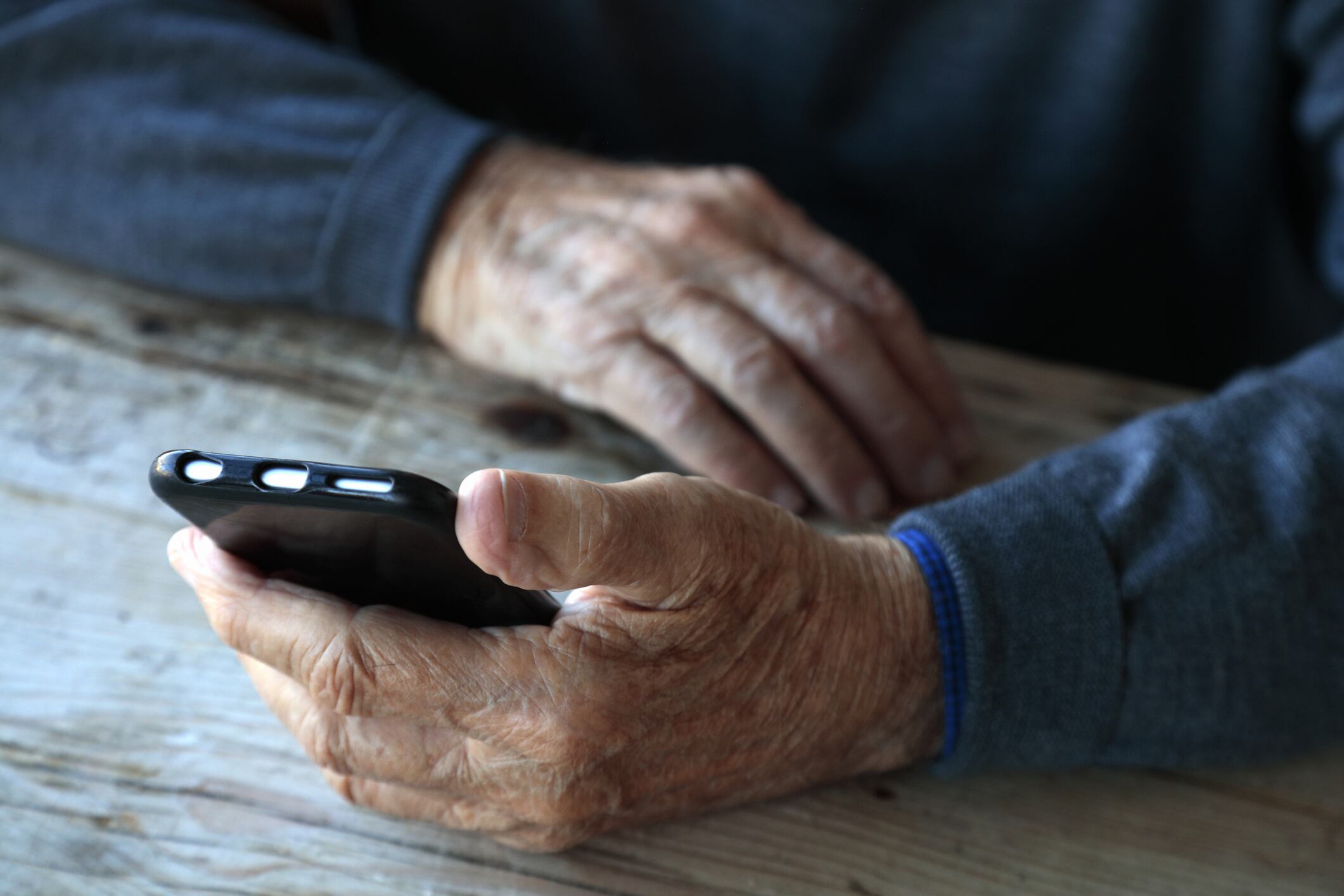 Un anciano sostiene un teléfono móvil