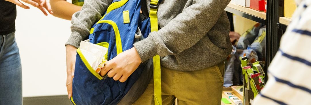 Una persona mete un producto de supermercado en una mochila