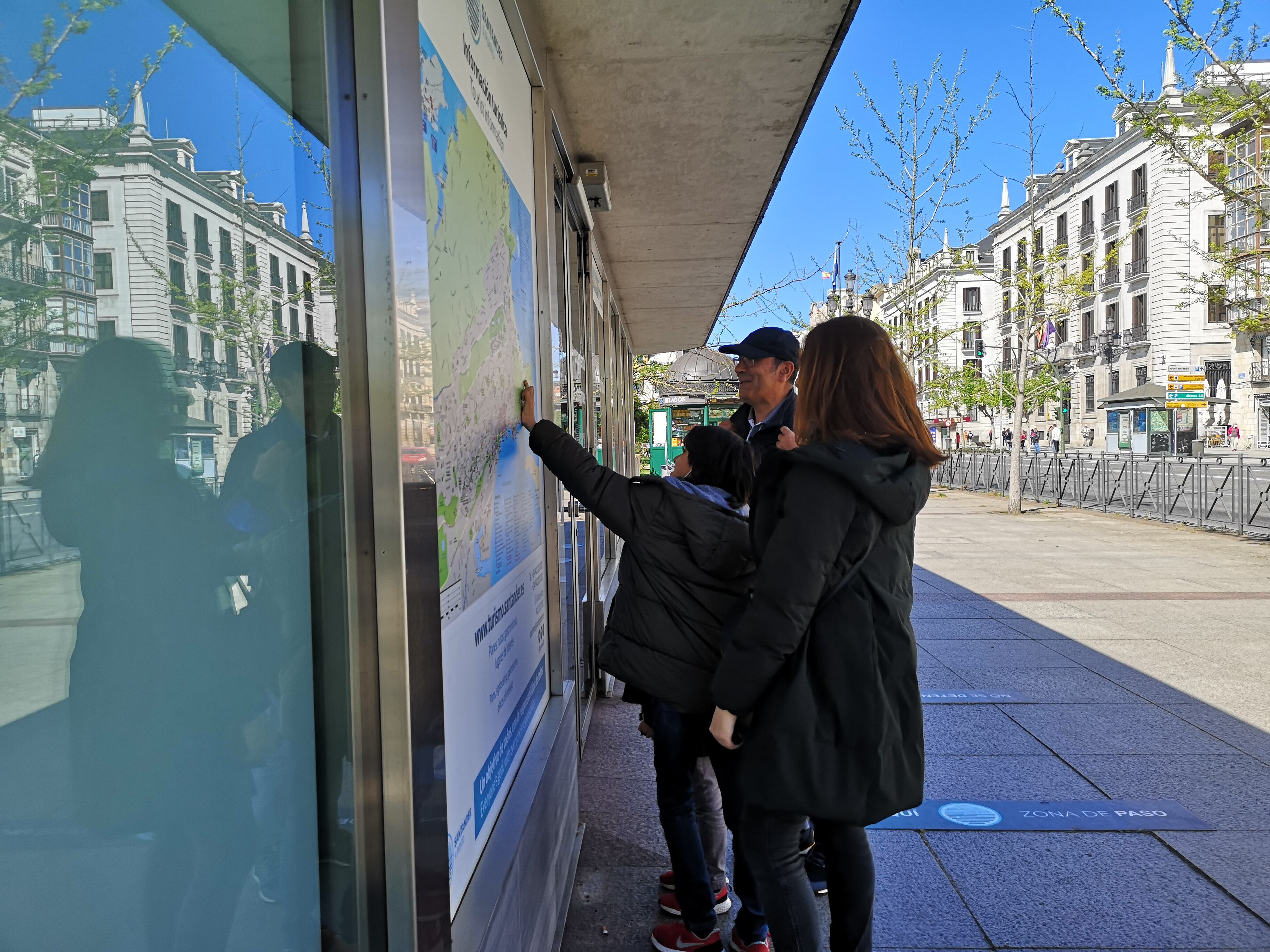 Una familia mira un mapa en la oficina de turismo de Santander.