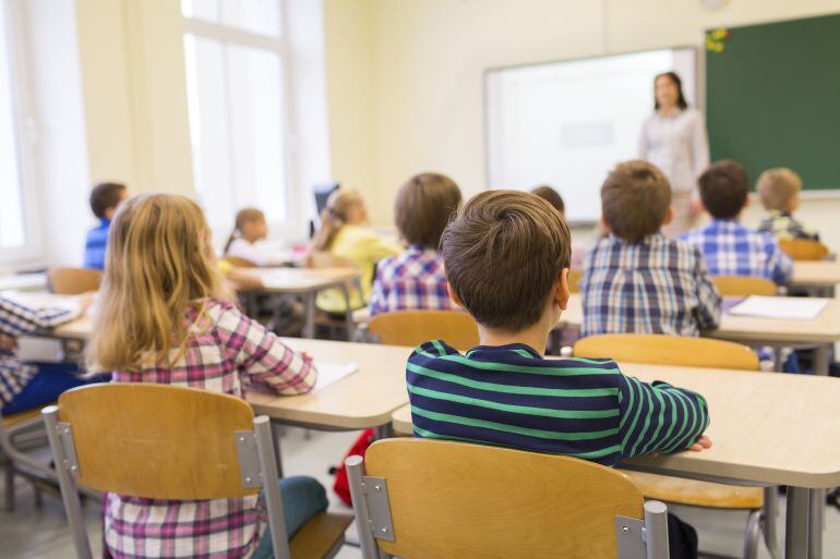 Un grupo de alumnos atiende a una profesora en el colegio. 