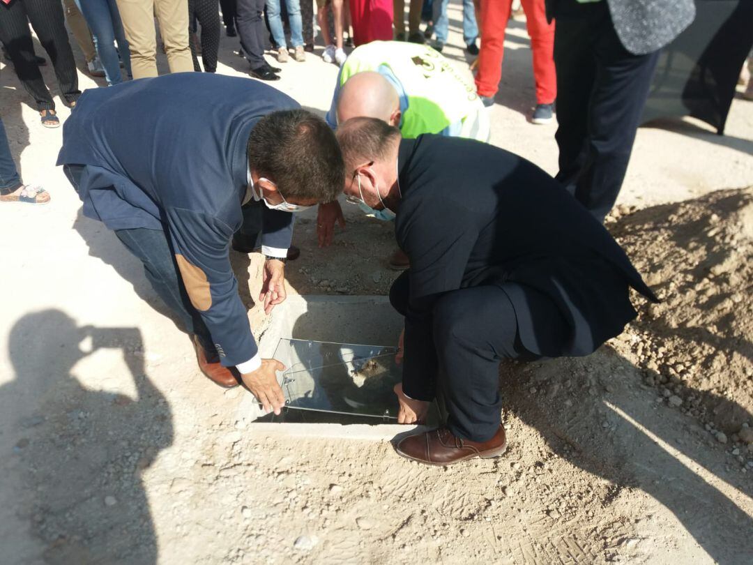 Momento en el que el presidente de la Diputación Provincial de Jaén, Francisco Reyes, izquierda, y el alcalde de Bedmar, Pablo Ruiz, introducen la urna en el hueco habilitado, acompañados por un trabajador de la empresa constructora