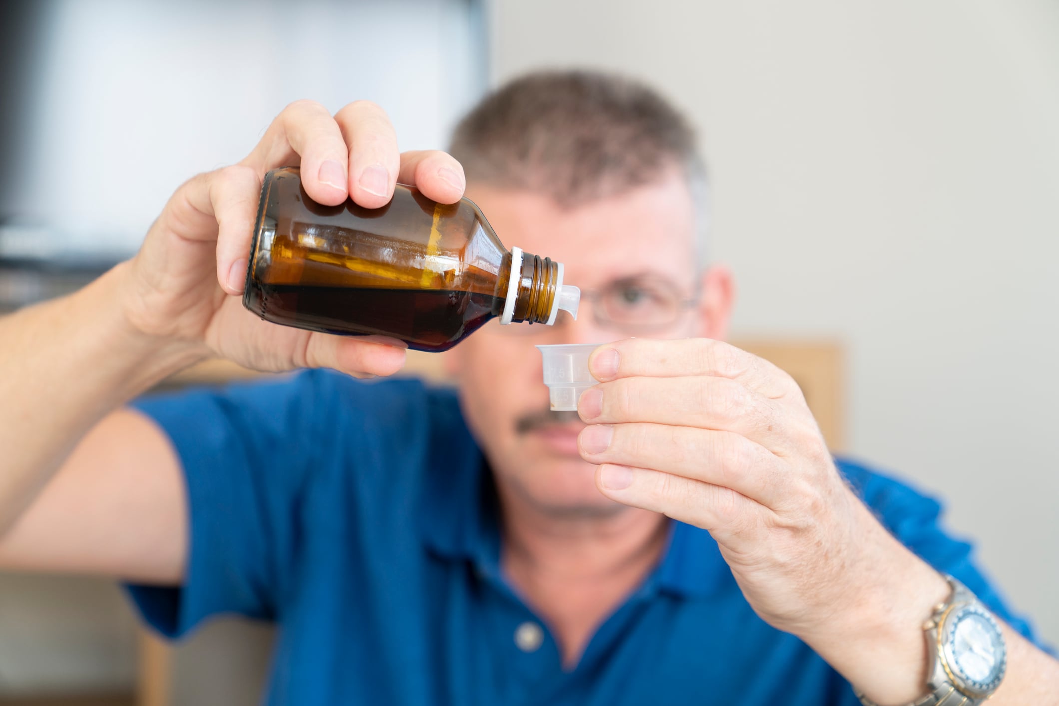 man pouring medicine into a measurning cup